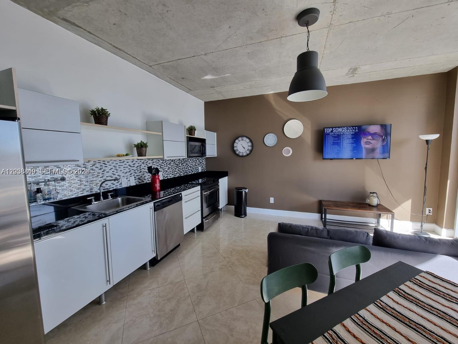 A modern open-concept kitchen and living area features white cabinets, stainless appliances, and concrete ceilings — 690 SW 1st Ct # 1827, Miami FL 33130, MIAMI, FL
