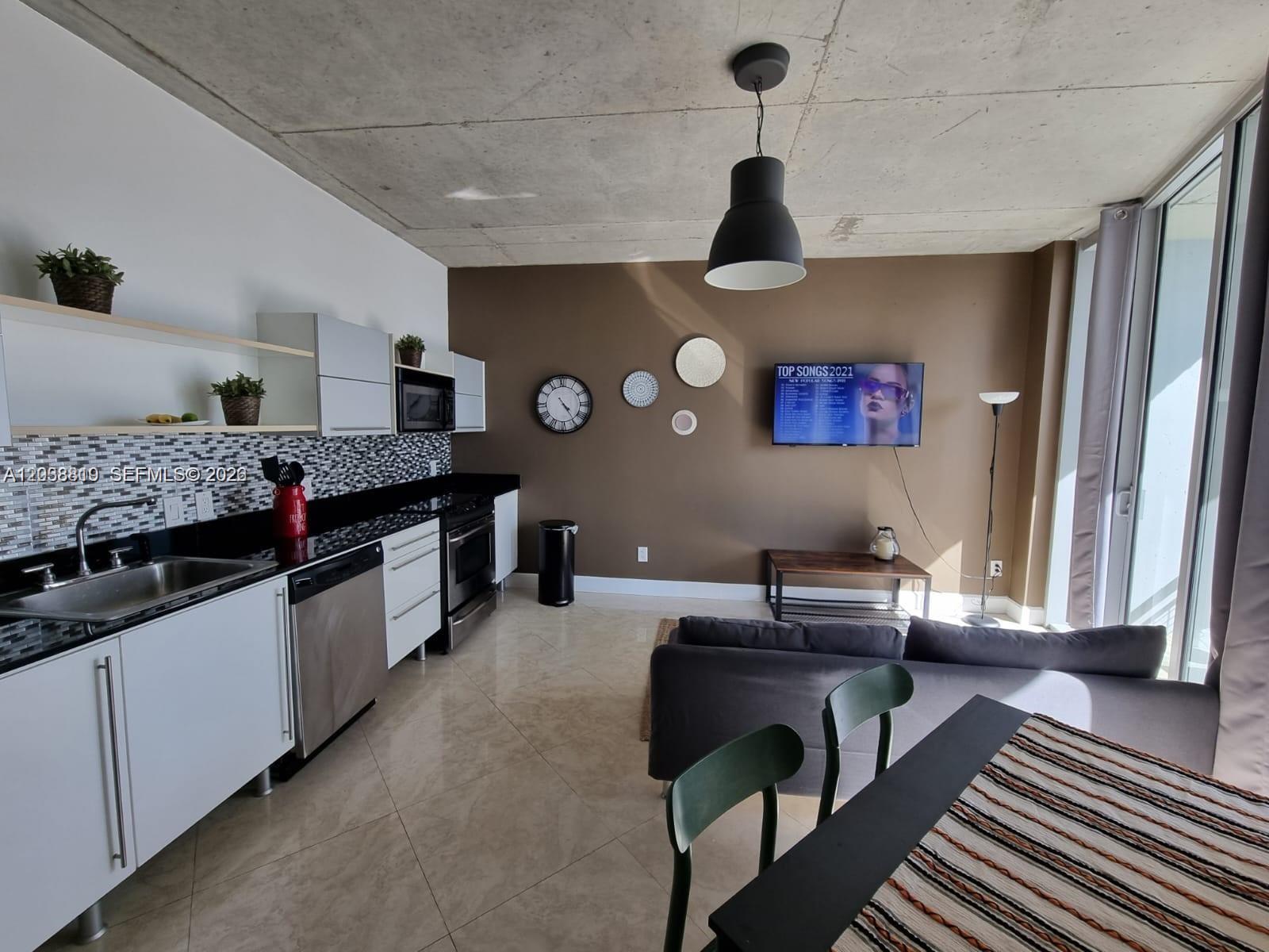An open-concept kitchen and living area features concrete ceilings, tile floors, and a wall-mounted television — 690 SW 1st Ct # 1827, Miami FL 33130, MIAMI, FL