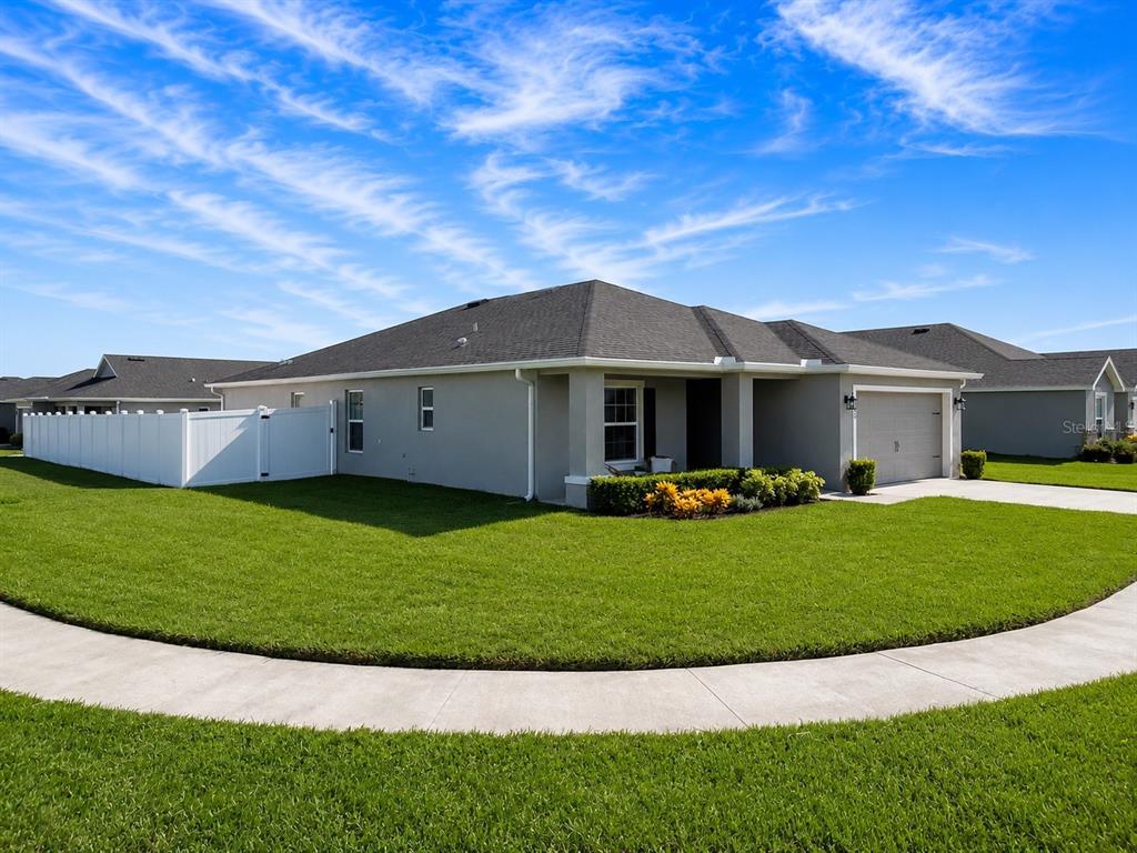 A single-story house with a gray exterior, a two-car garage, and a white privacy fence — 1002 PAISLEY STREET, LAKE ALFRED, FL