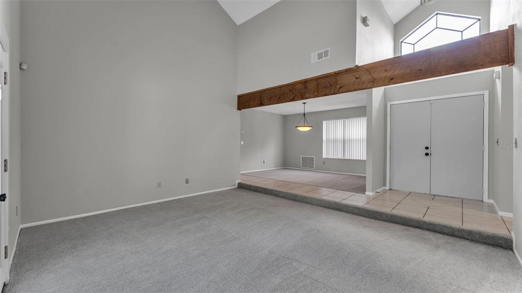 A living room features a vaulted ceiling, a wooden beam, and a sunken carpeted area — 2331 PEPPERCORN STREET, KISSIMMEE, FL