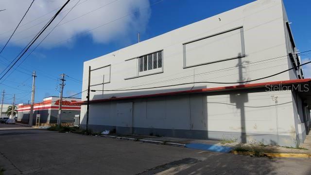 A two-story commercial building with a light-colored facade stands next to an AutoZone store — PR 2 INT DELICIAS ST, ARECIBO, PR