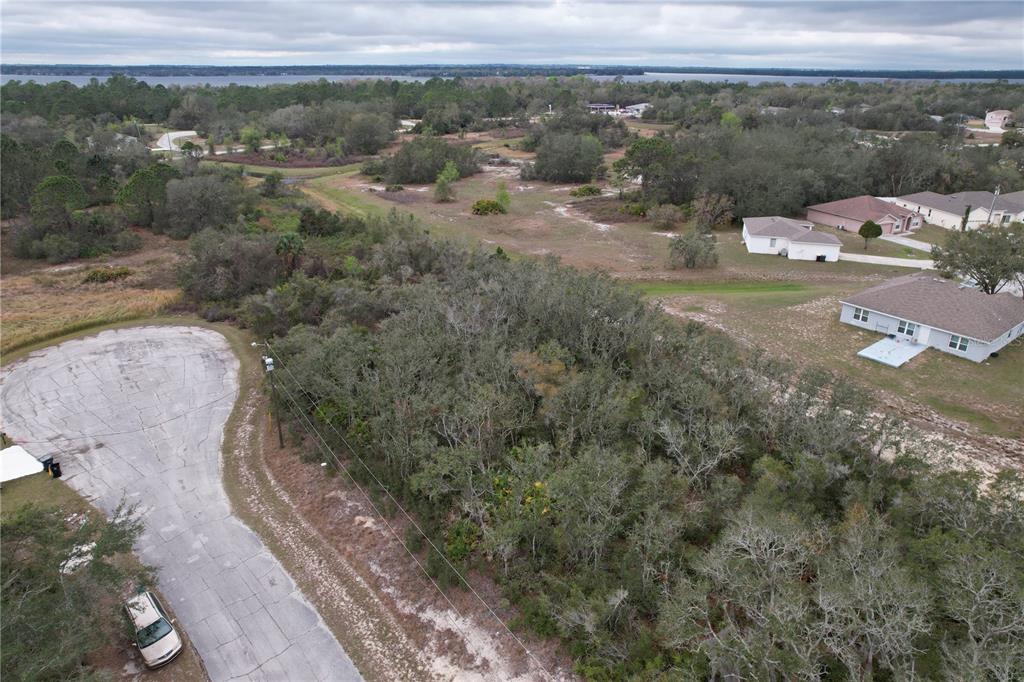 An aerial view shows a wooded residential lot adjacent to a cul-de-sac and nearby houses — 509 SARASOTA LANE, KISSIMMEE, FL