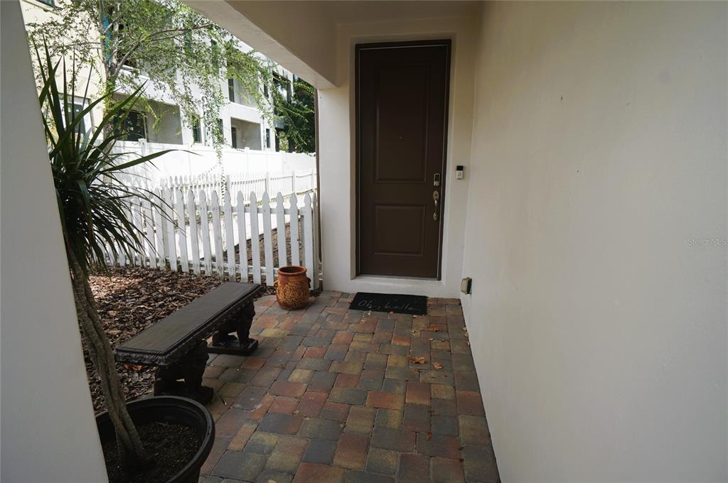 A paved entryway features a dark brown front door, a bench, and a potted plant — 4250 W CARMEN STREET, TAMPA, FL