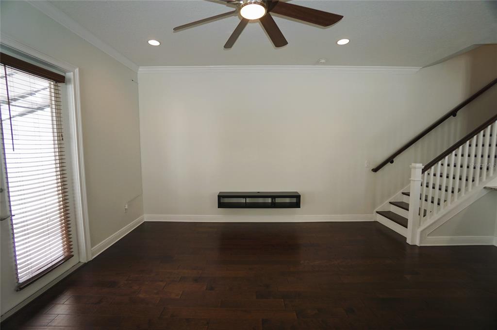 A living room features dark hardwood floors, a floating media console, and a staircase — 4250 W CARMEN STREET, TAMPA, FL