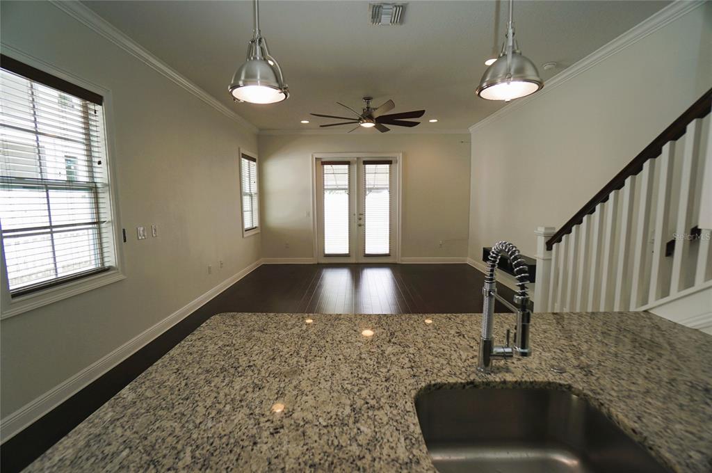 A kitchen island with a granite countertop overlooks a living area with dark wood floors — 4250 W CARMEN STREET, TAMPA, FL