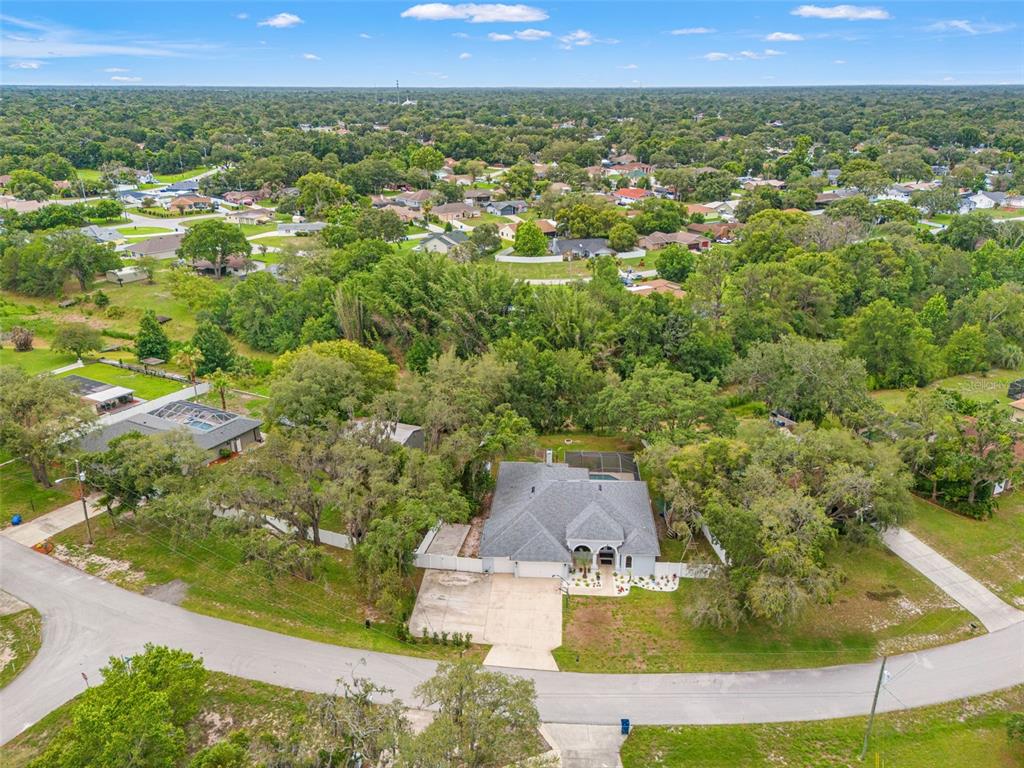 An aerial view shows a single-story house with a gray roof and driveway — 9076 GALLUP ROAD, SPRING HILL, FL