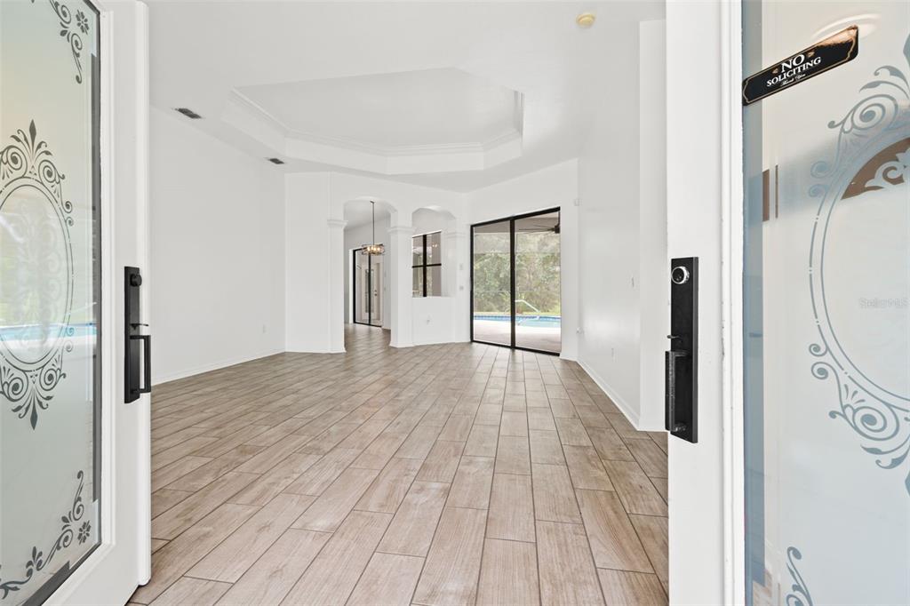 An entryway looking into a living area with wood-look tile floors and sliding glass doors — 9076 GALLUP ROAD, SPRING HILL, FL
