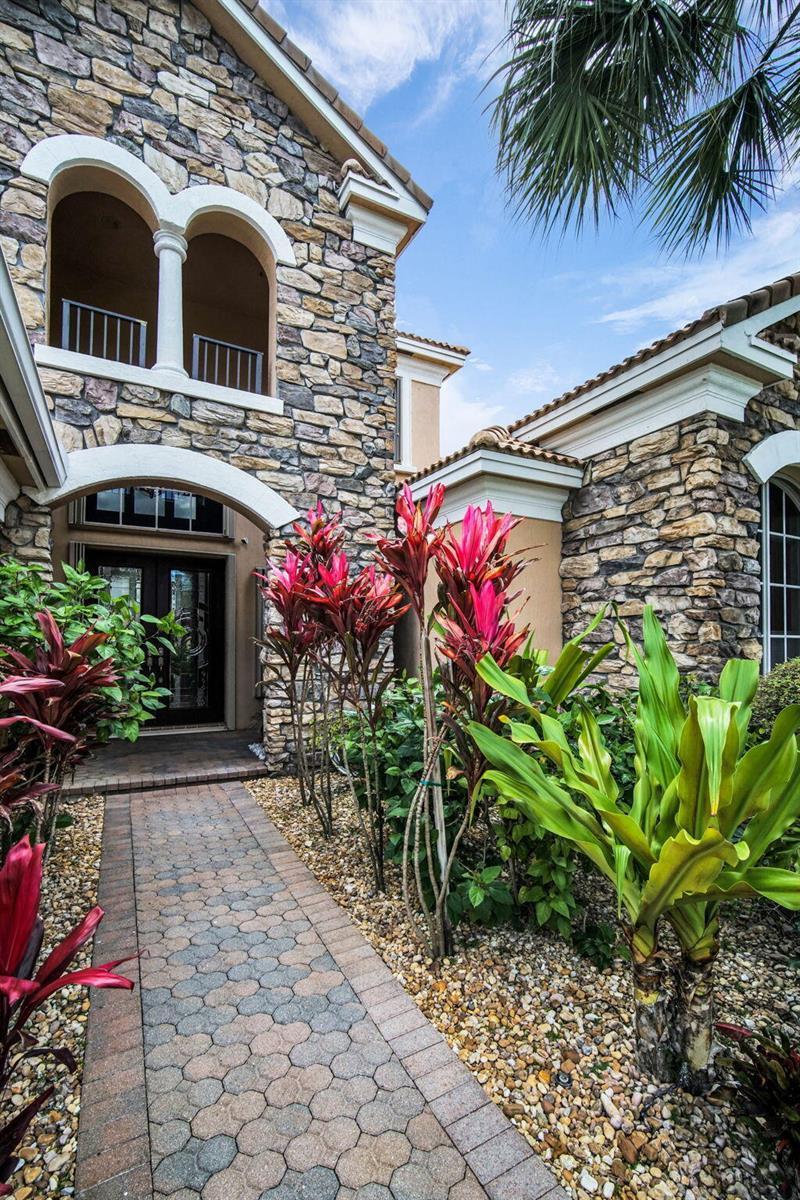 A stone-clad house exterior features a paved walkway leading to a dark double-door entrance — 9192 Pineville Drive, Lake Worth FL 33467, LAKE WORTH, FL