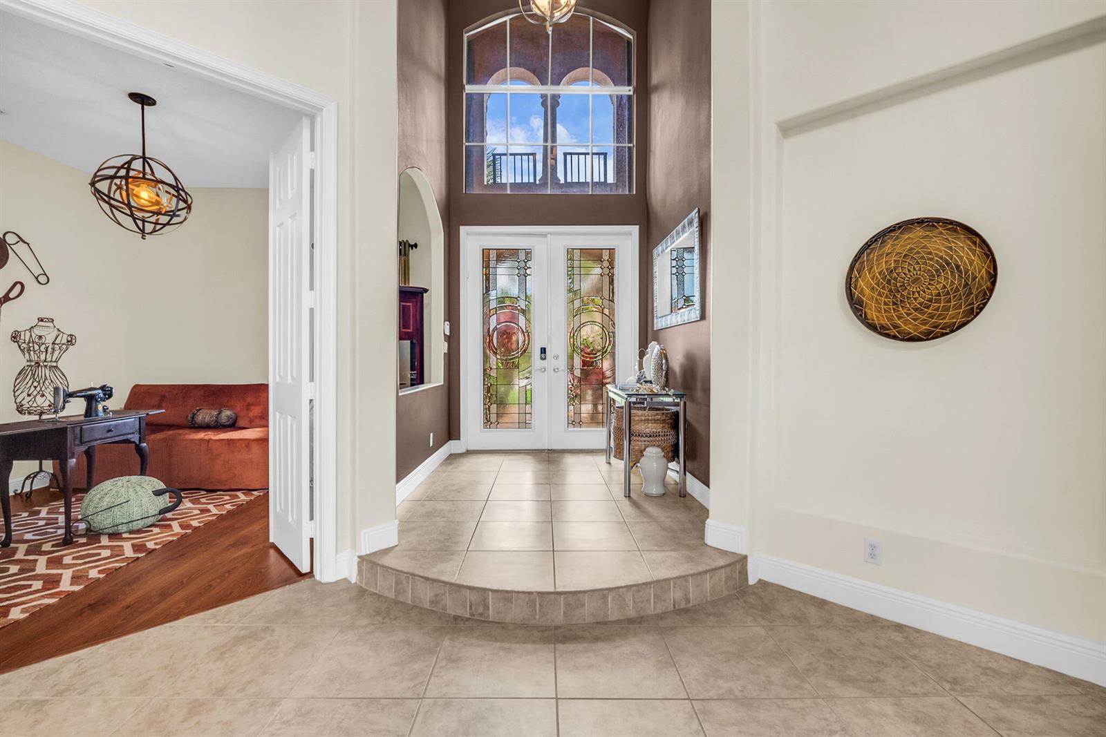 A tiled entryway features a raised foyer, double glass doors, and a high arched window — 9192 Pineville Drive, Lake Worth FL 33467, LAKE WORTH, FL