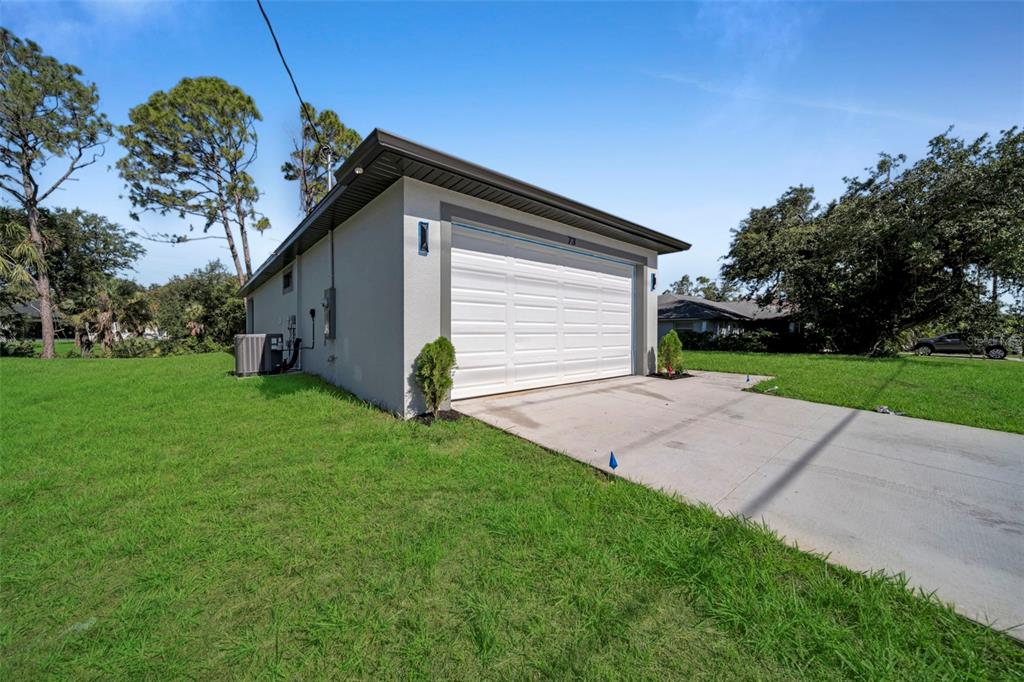A detached garage with a white door and concrete driveway sits on a grassy lot — 73 FLAMINGO BOULEVARD, PORT CHARLOTTE, FL