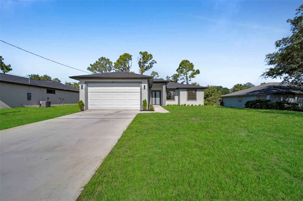 A single-story house with a white garage door, gray exterior, and a concrete driveway — 73 FLAMINGO BOULEVARD, PORT CHARLOTTE, FL