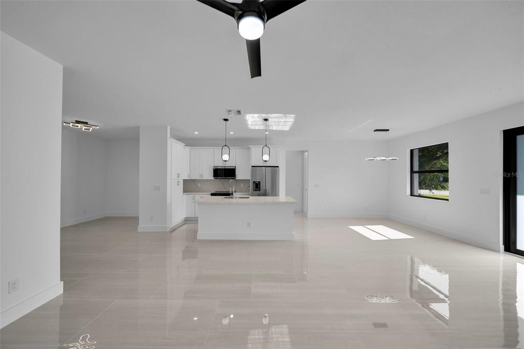 A bright, open-concept kitchen and living area features white cabinetry, a central island, and tile flooring — 73 FLAMINGO BOULEVARD, PORT CHARLOTTE, FL