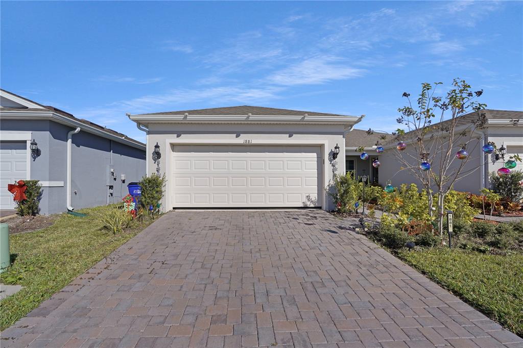 A paved driveway leads to a single-story house with a two-car garage — 1881 SPRING SHOWER CIRCLE, KISSIMMEE, FL