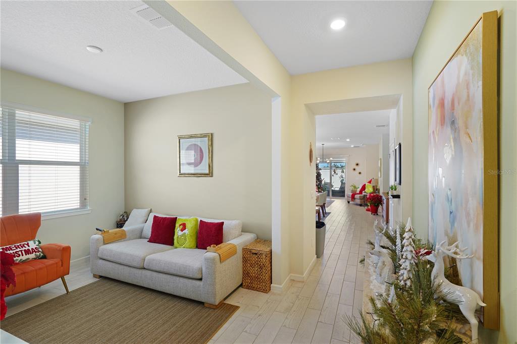 A living room with a sofa and armchair leads into a hallway with tiled floors — 1881 SPRING SHOWER CIRCLE, KISSIMMEE, FL