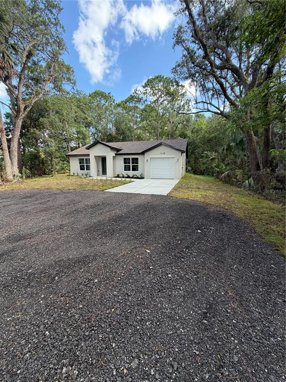 A single-story house with a white exterior, a garage, and a gravel driveway — 1438 LAKE HARNEY, GENEVA, FL