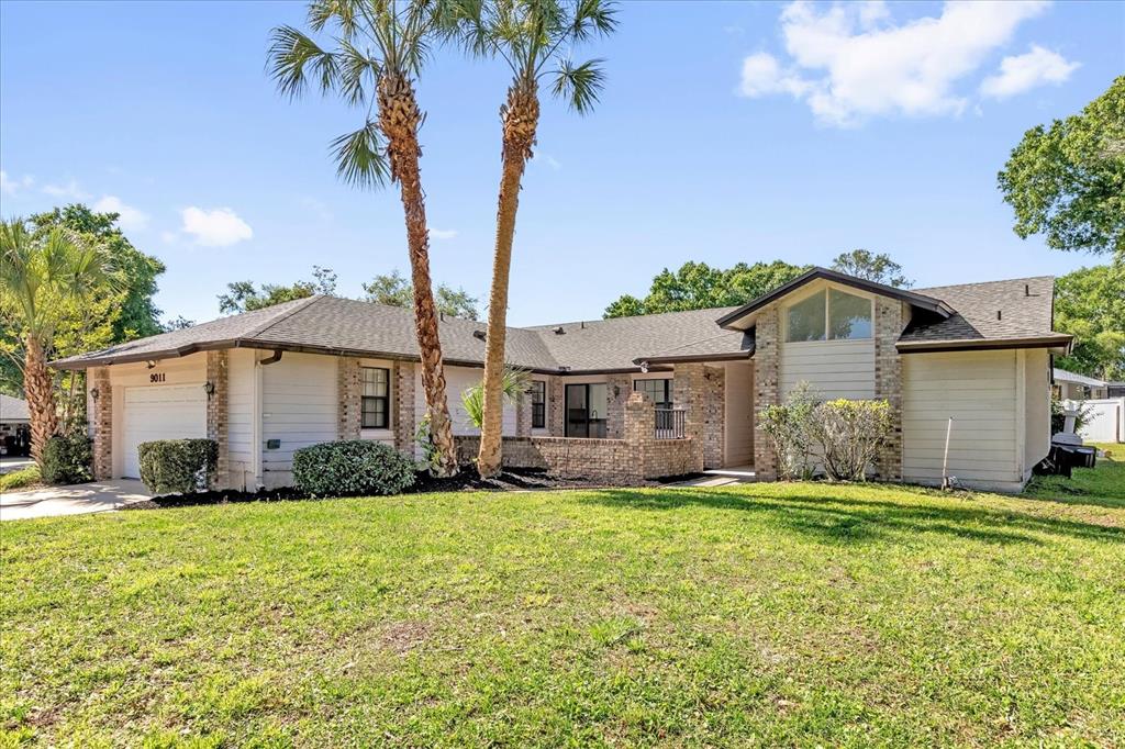 A single-story house with a brick and siding exterior, a two-car garage, and palm trees — 9011 CHAPMAN OAK COURT, WINDERMERE, FL
