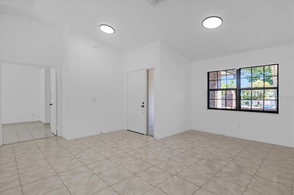 An empty room with white walls, tiled floors, two ceiling lights, and a front door — 9011 CHAPMAN OAK COURT, WINDERMERE, FL
