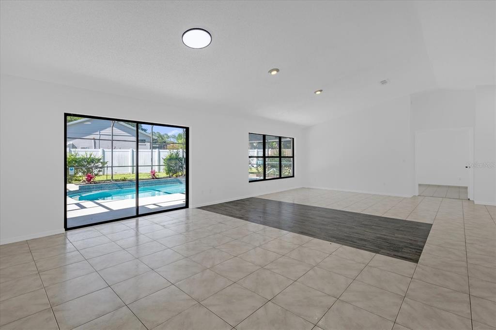 An open-concept living area features tile flooring, a dark wood-look inlay, and sliding glass doors — 9011 CHAPMAN OAK COURT, WINDERMERE, FL