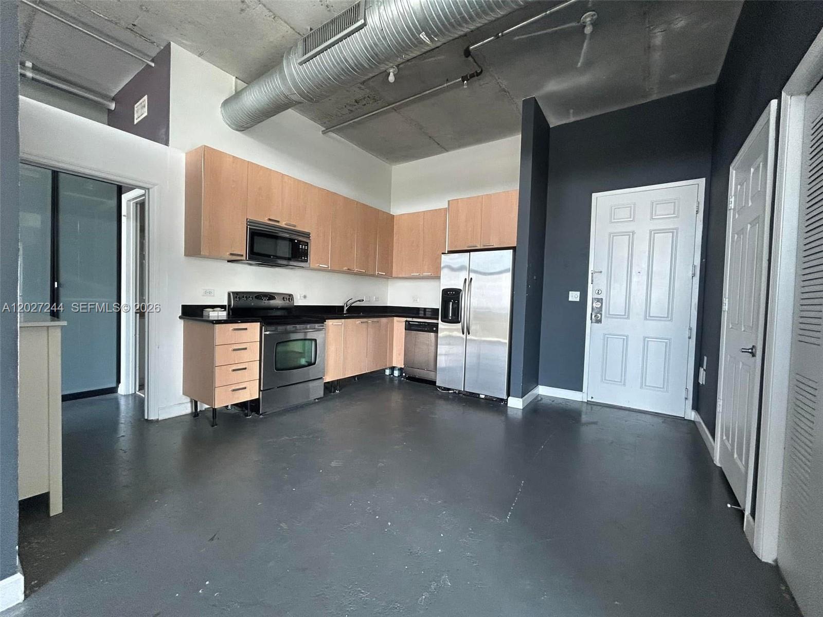 A kitchen with light wood cabinets, stainless steel appliances, and exposed industrial ceiling ductwork — 2100 Van Buren St # 506, Hollywood FL 33020, HOLLYWOOD, FL