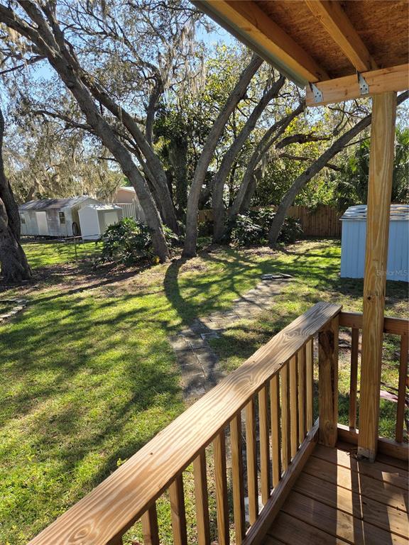 A wooden deck overlooks a grassy backyard with large trees and two small storage sheds — 1846 FRUITLAND PARK BOULEVARD, FRUITLAND PARK, FL