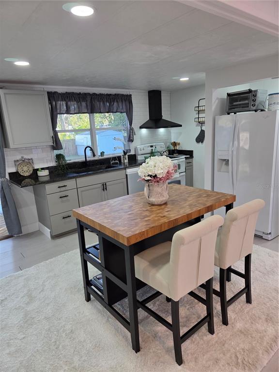 A kitchen features gray cabinets, a butcher block island with two chairs, and white appliances — 1846 FRUITLAND PARK BOULEVARD, FRUITLAND PARK, FL