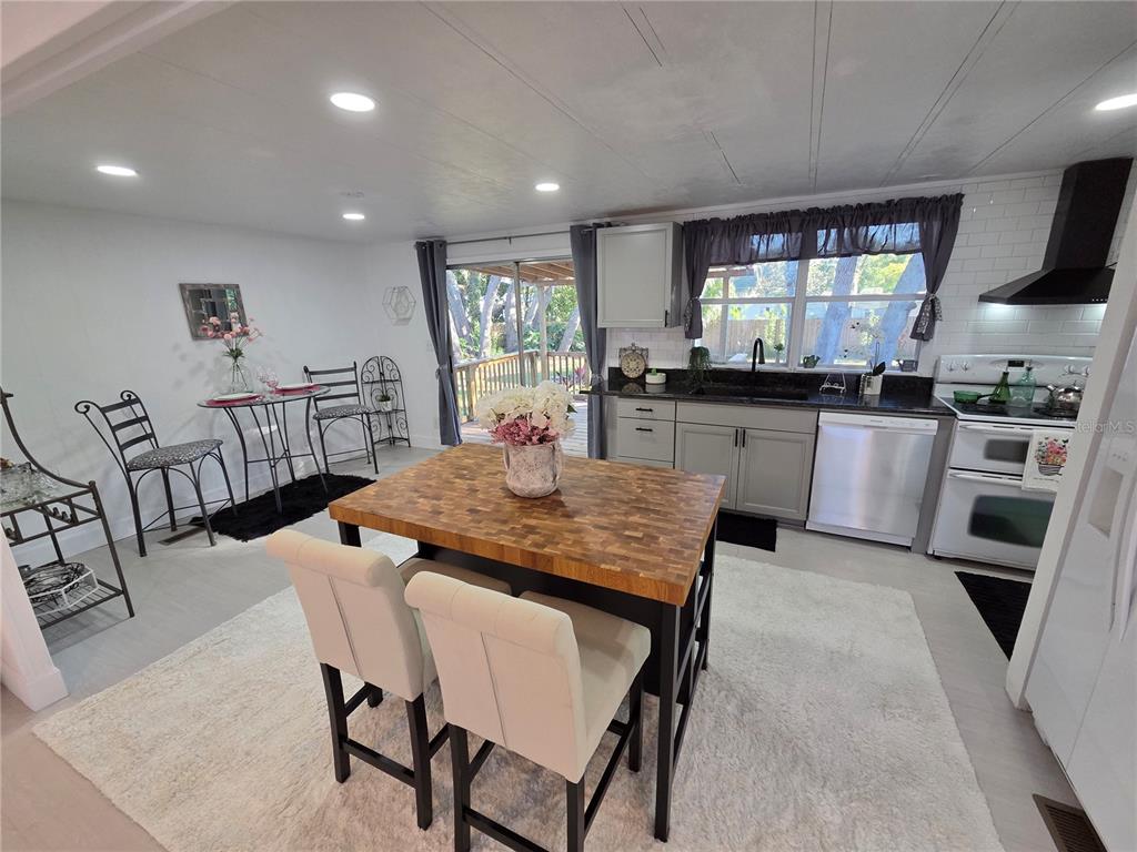A kitchen features a butcher block island, gray cabinetry, and a dining area with stools — 1846 FRUITLAND PARK BOULEVARD, FRUITLAND PARK, FL