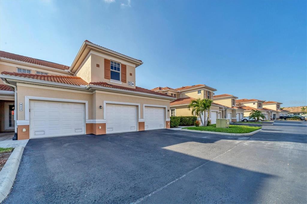 A row of tan townhouses with red tile roofs and multiple garage doors under a sky — 240 W END DRIVE UNIT 923, PUNTA GORDA, FL