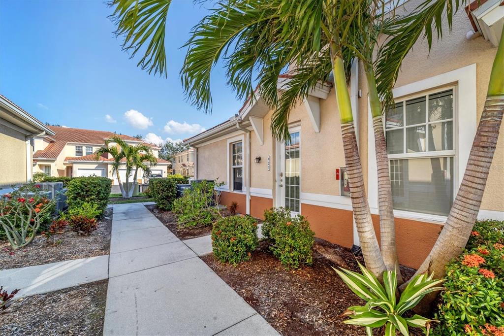 A sidewalk leads to the entrance of a tan stucco building with palm trees — 240 W END DRIVE UNIT 923, PUNTA GORDA, FL
