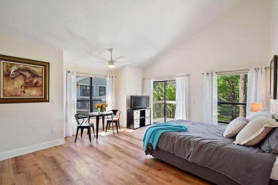 A bedroom with wood-look flooring, a vaulted ceiling, a bed, and a small dining area — 11863 Wimbledon Circle # 508, Wellington FL 33414, WELLINGTON, FL