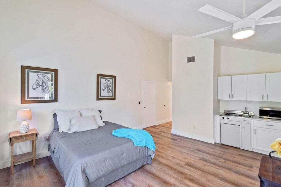 A studio apartment featuring a bed, a small kitchenette, and wood-look flooring — 11863 Wimbledon Circle # 508, Wellington FL 33414, WELLINGTON, FL