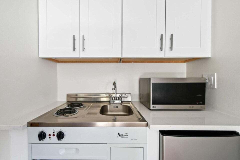 A compact kitchenette features white cabinets, a stainless steel sink, two burners, and a microwave — 11863 Wimbledon Circle # 508, Wellington FL 33414, WELLINGTON, FL