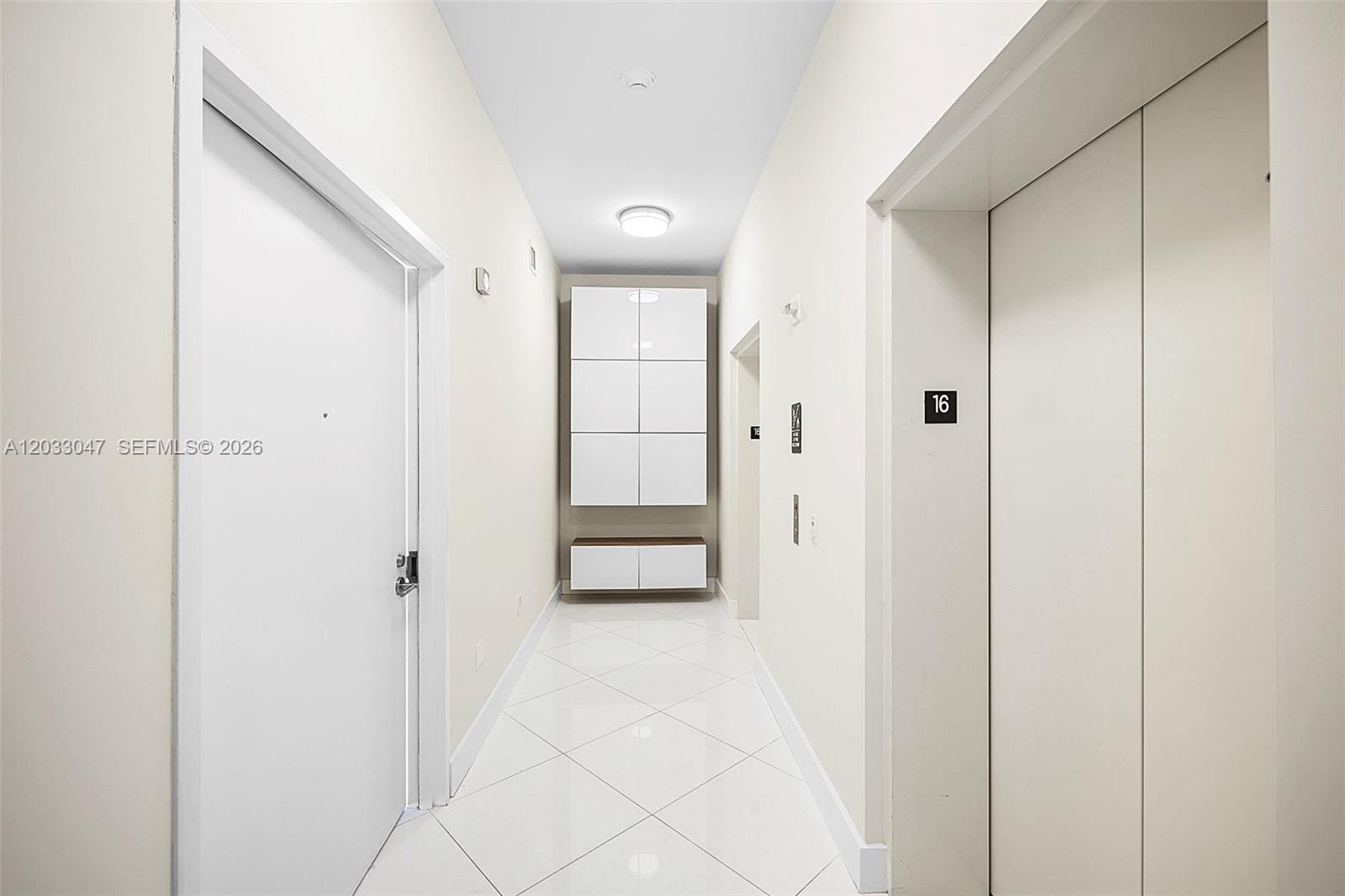 A bright hallway features white tiled floors, a white storage unit, and an elevator door — 2020 N Bayshore Dr # 1602, Miami FL 33137, MIAMI, FL