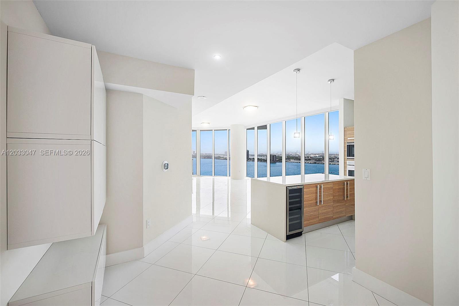 A modern kitchen with wood cabinets and a wine cooler overlooks a waterfront view — 2020 N Bayshore Dr # 1602, Miami FL 33137, MIAMI, FL