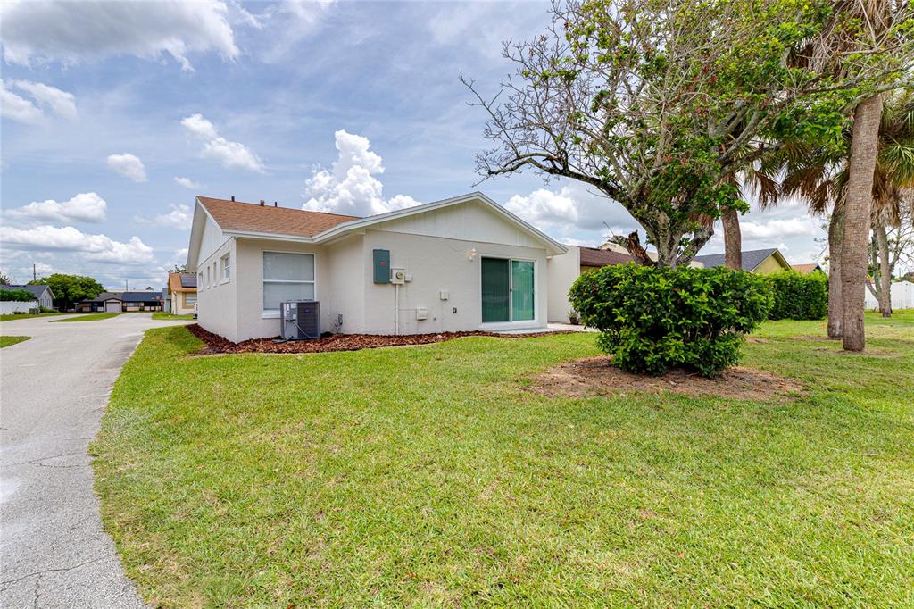 The exterior of a light-colored single-story house features a sliding glass door and lawn — 1100 CALANDA AVENUE, ORLANDO, FL