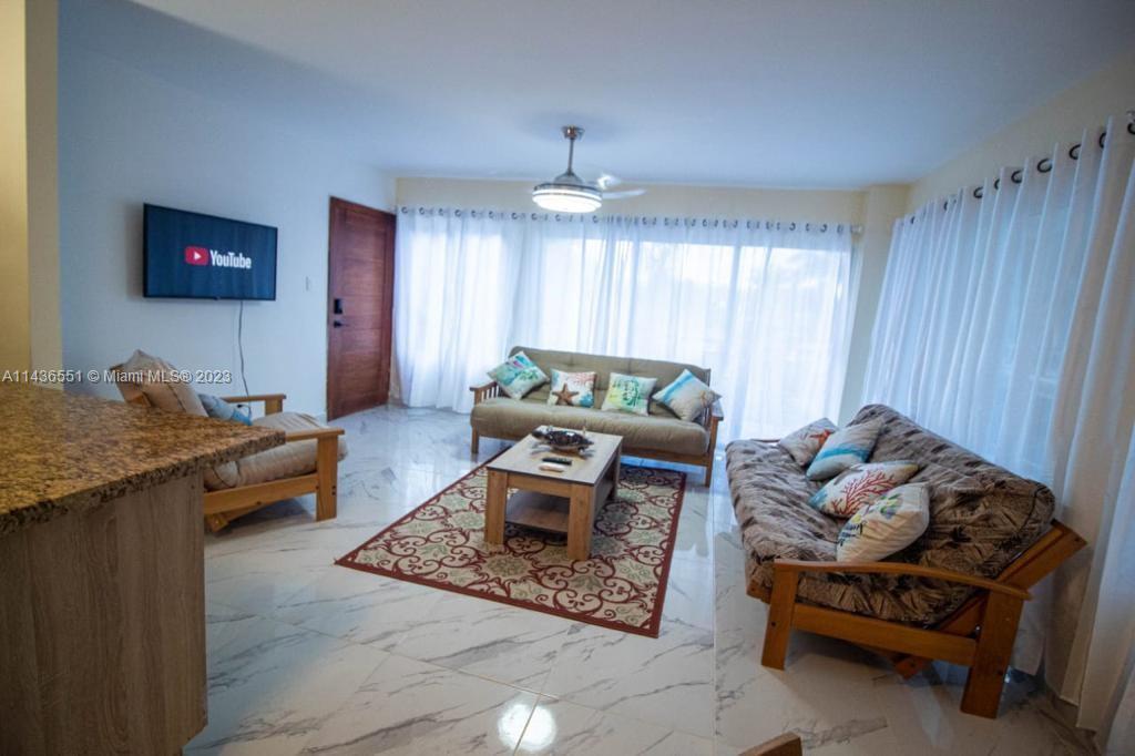 A living room features white marble floors, a wooden coffee table, and two futon sofas — 1234 Carretera Sanchez # 1G, DR, DR