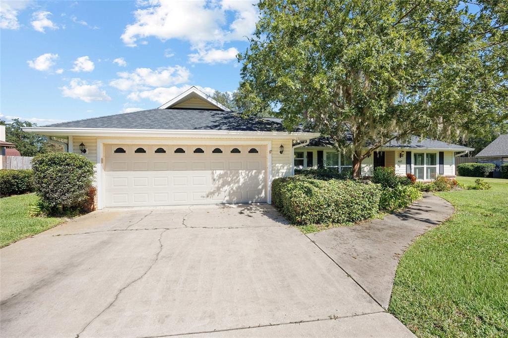 A single-story house with a two-car garage, light siding, and a large shade tree — 4517 SE 2ND PLACE, OCALA, FL