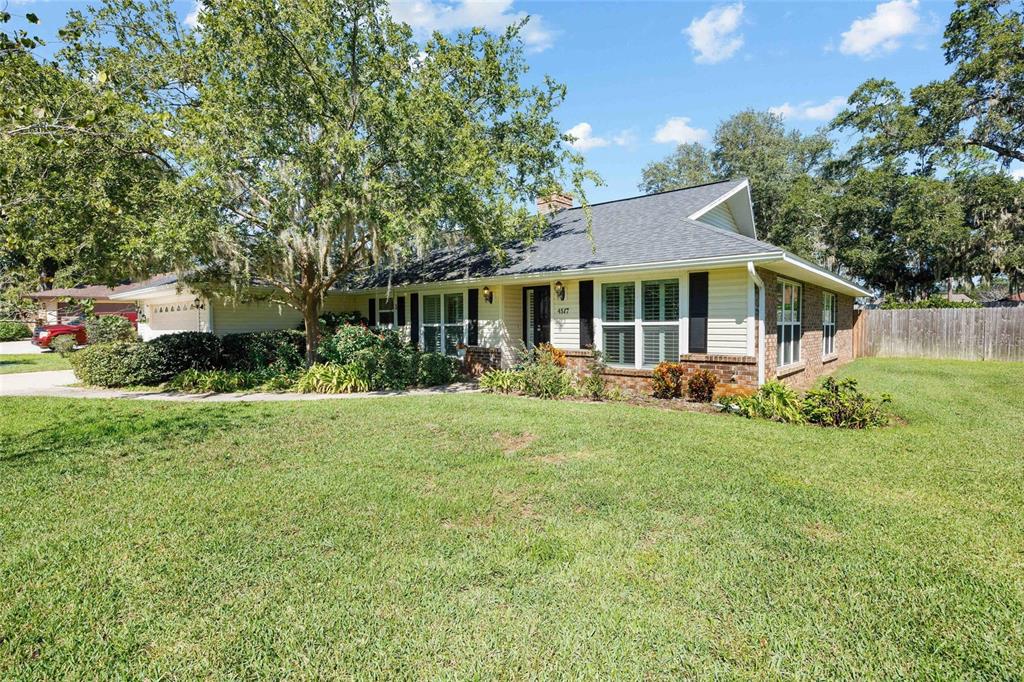A single-story house with light siding, brick accents, and a large tree in the yard — 4517 SE 2ND PLACE, OCALA, FL