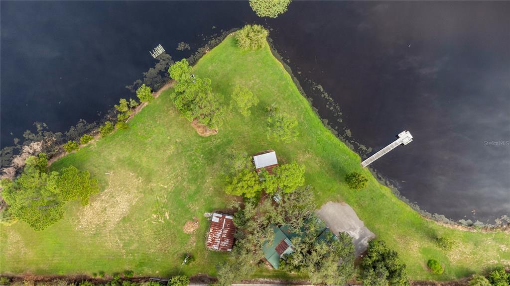 An aerial view shows a house and outbuildings on a grassy point of land — 5020 RONALD REAGAN PARKWAY, DAVENPORT, FL