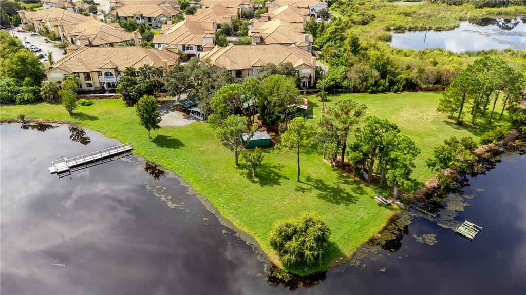 An aerial view shows a grassy peninsula with trees and a dock extending into water — 5020 RONALD REAGAN PARKWAY, DAVENPORT, FL