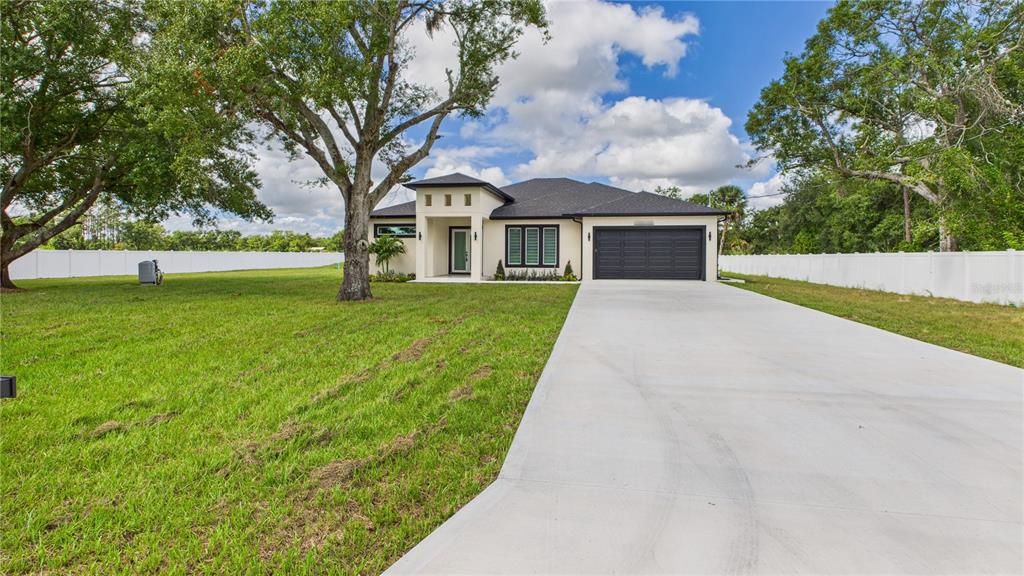 A single-story house with a black garage door and a concrete driveway sits on grass — 1515 30TH STREET SE, RUSKIN, FL