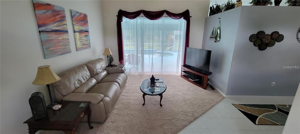 A living room features a beige leather sofa, a coffee table, and a television stand — 193 SPORTSMAN ROAD, ROTONDA WEST, FL