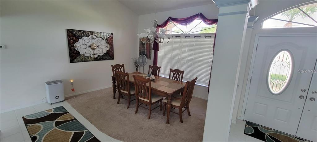 A dining area features a wooden table with six chairs, a chandelier, and carpeted flooring — 193 SPORTSMAN ROAD, ROTONDA WEST, FL