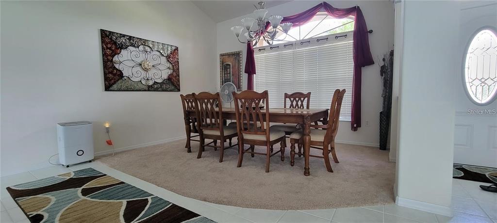 A dining room features a wooden table with six chairs on a carpeted area — 193 SPORTSMAN ROAD, ROTONDA WEST, FL