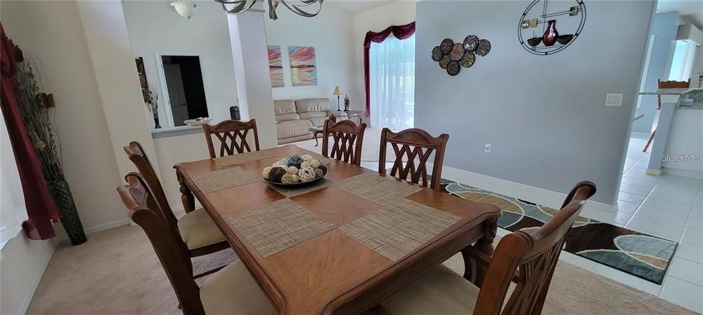 A dining room features a wooden table with chairs and a view into the living area — 193 SPORTSMAN ROAD, ROTONDA WEST, FL