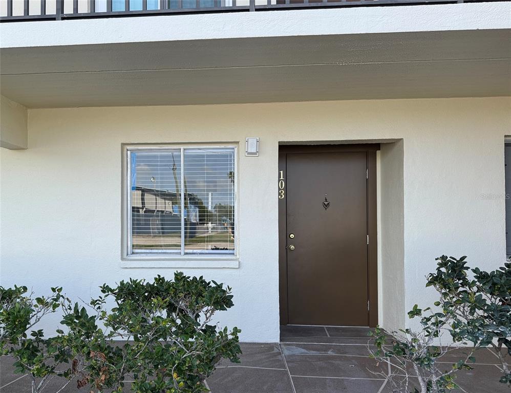 A ground-level apartment entrance features a brown door labeled 103 next to a window — 4435 1ST STREET NE UNIT 103, ST PETERSBURG, FL