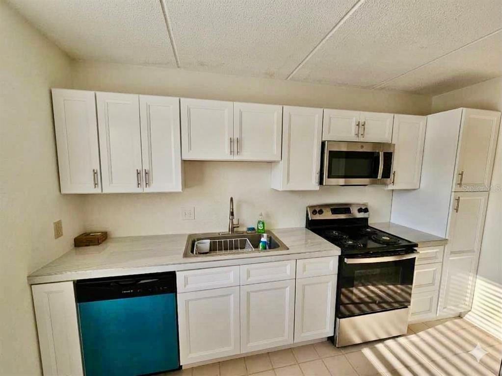 A kitchen features white cabinets, stainless steel appliances, and light-colored countertops — 4435 1ST STREET NE UNIT 103, ST PETERSBURG, FL