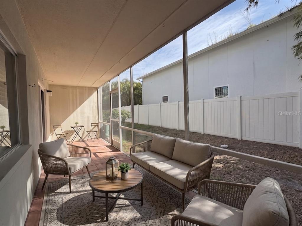 A screened-in patio features outdoor furniture, a rug, and a view of a fenced backyard — 4435 1ST STREET NE UNIT 103, ST PETERSBURG, FL