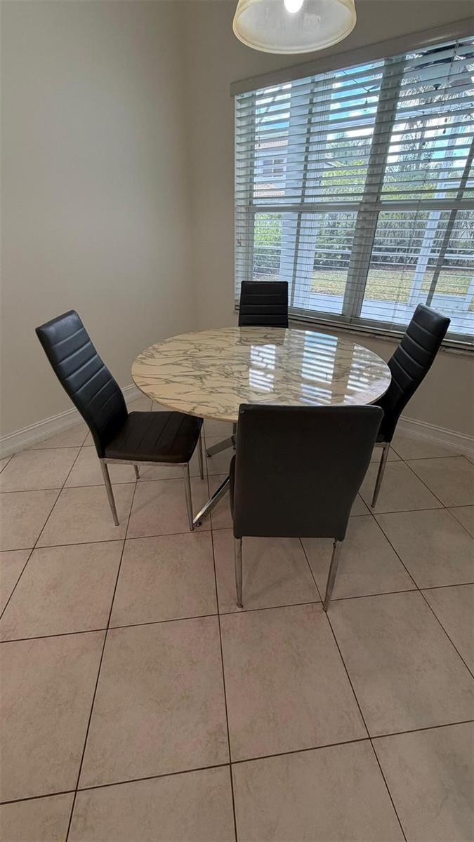 A dining area features a round marble-topped table with four black chairs on tiled floors — 4015 Lyndhurst I # 4015, Deerfield Beach FL 33442, DEERFIELD BEACH, FL