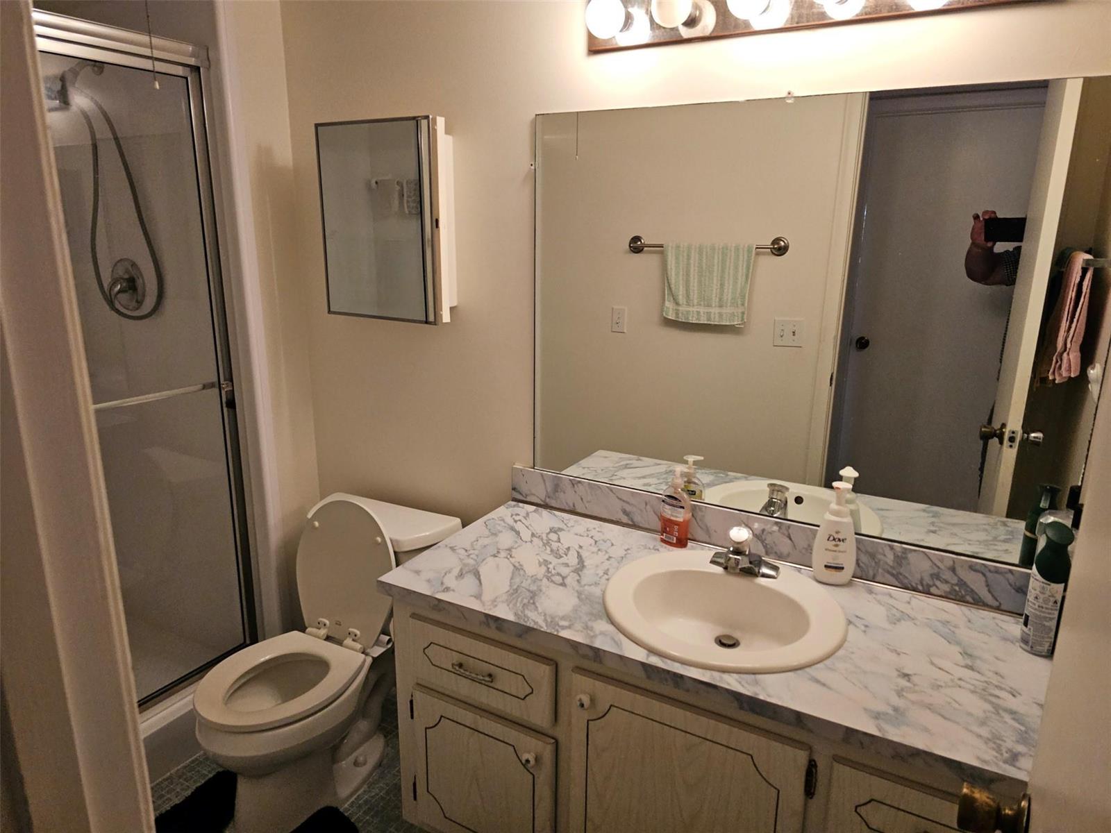 A bathroom features a marble-patterned vanity countertop, a toilet, and a glass-enclosed shower stall — 4015 Lyndhurst I # 4015, Deerfield Beach FL 33442, DEERFIELD BEACH, FL