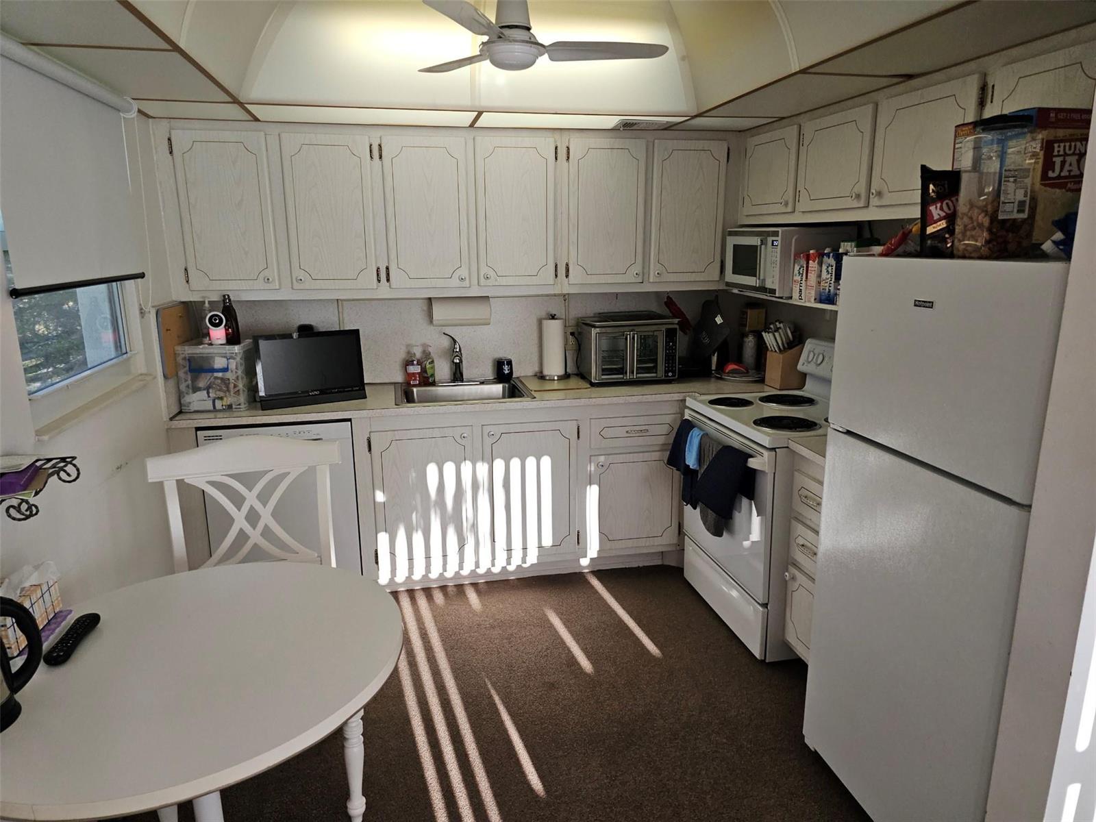 A kitchen with white cabinets, a white stove, a refrigerator, and a small dining table — 4015 Lyndhurst I # 4015, Deerfield Beach FL 33442, DEERFIELD BEACH, FL